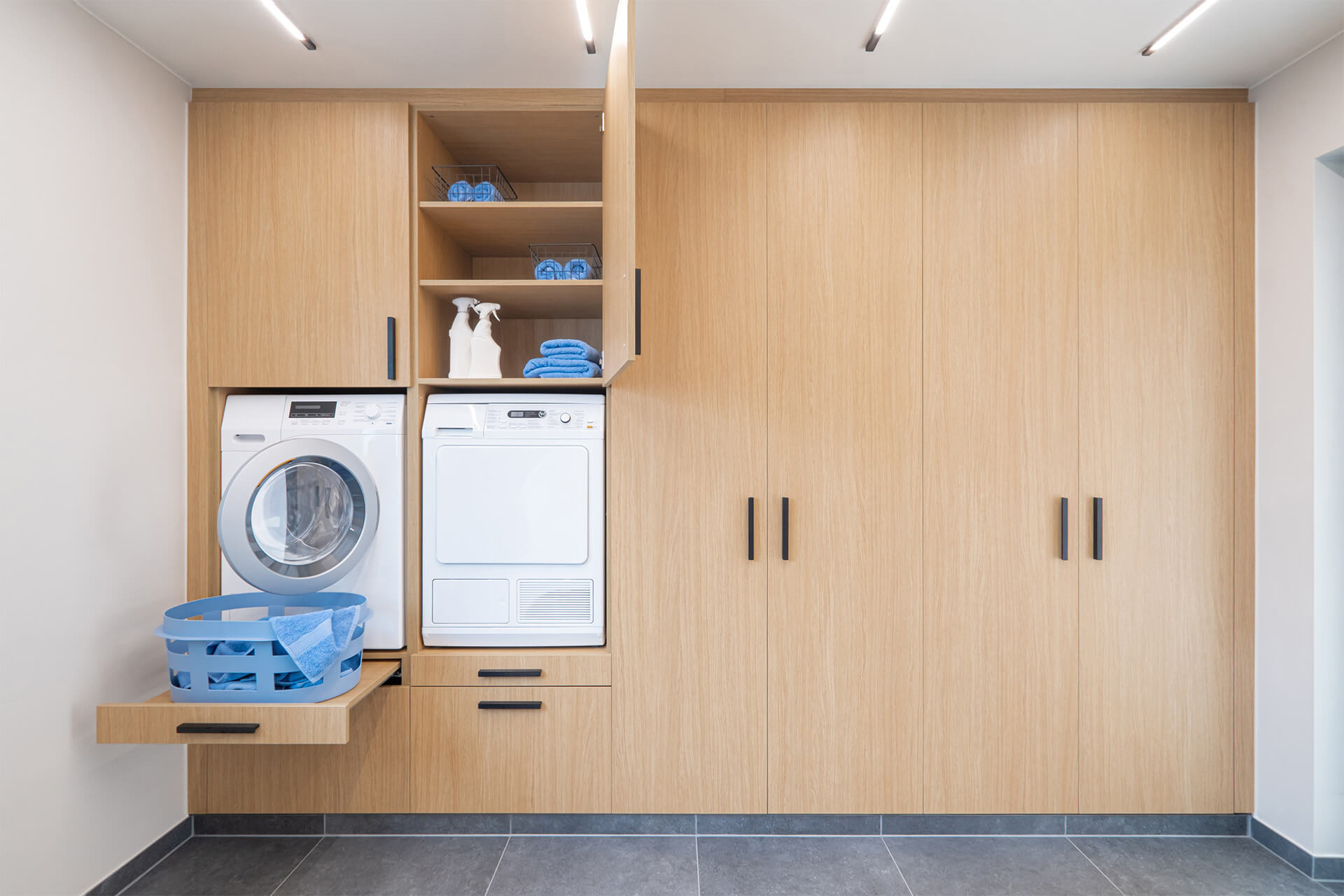 Een hoge waskast met wasmachine en droogkast in een berging