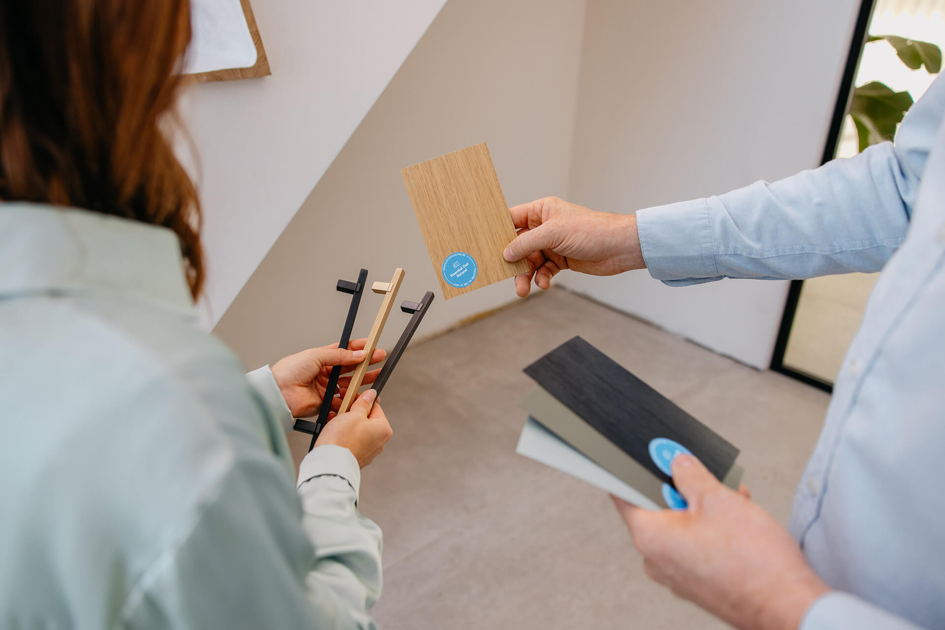 Man toont kleurstaal aan vrouw die handgrepen van Maatkasten Online vasthoudt