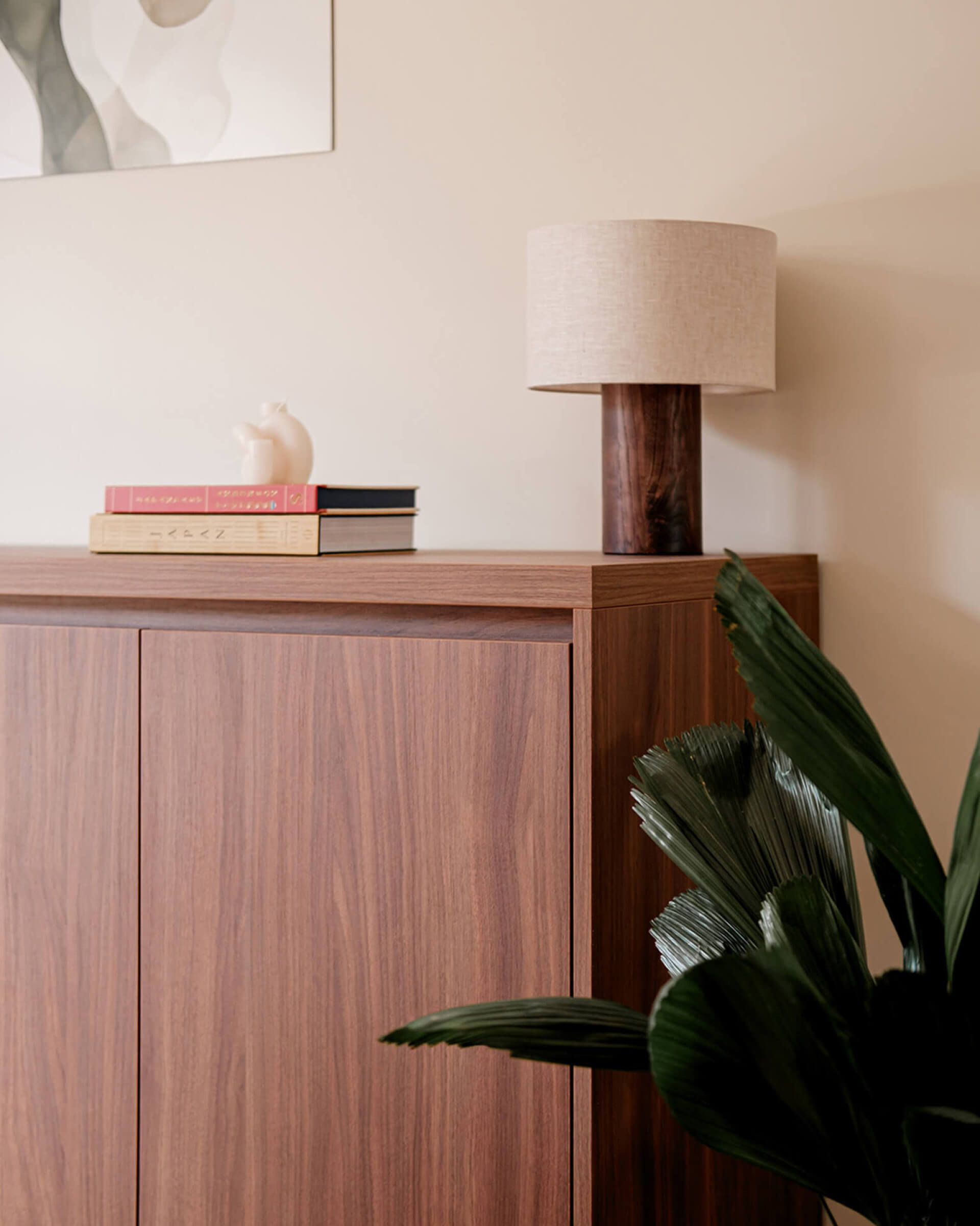 Commode in kleur walnut gedecoreerd met boeken en een lamp